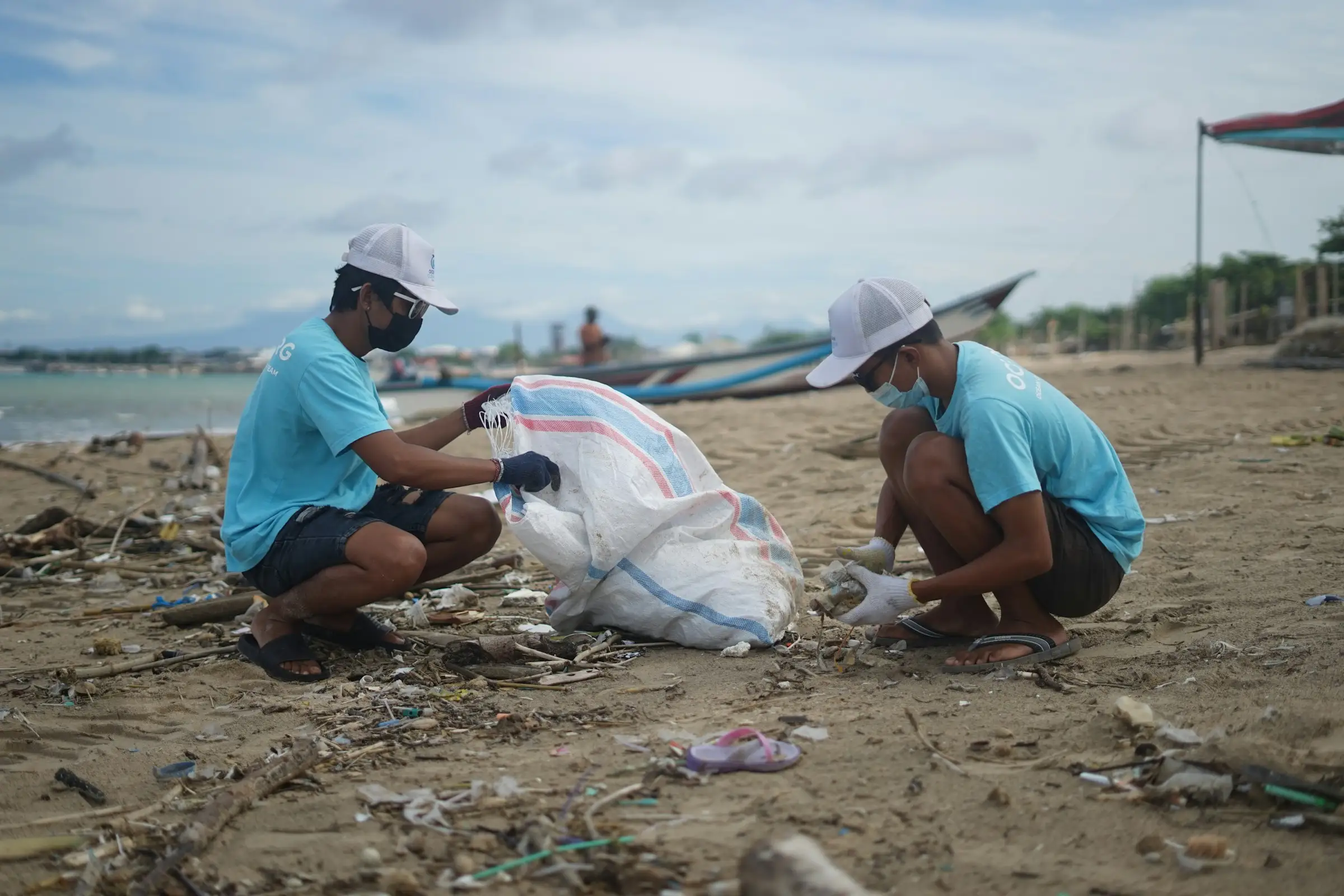 Two volunteers collecting plastic waste on a beach